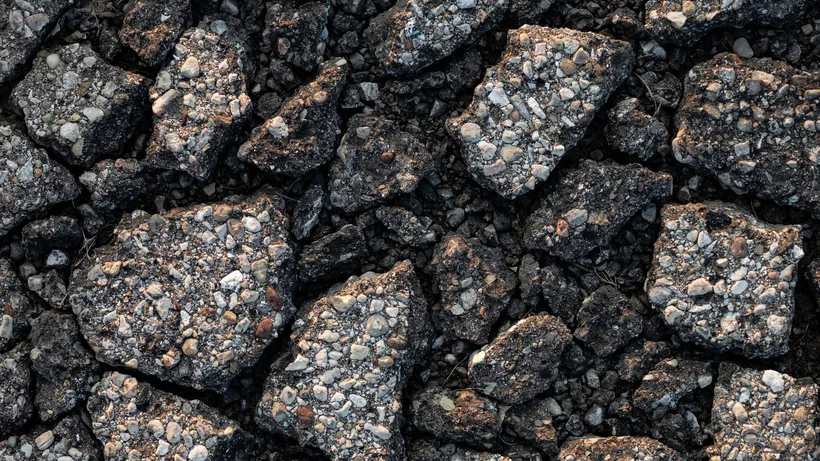 Pothole and raveled asphalt showing loose aggregate at the broken edge