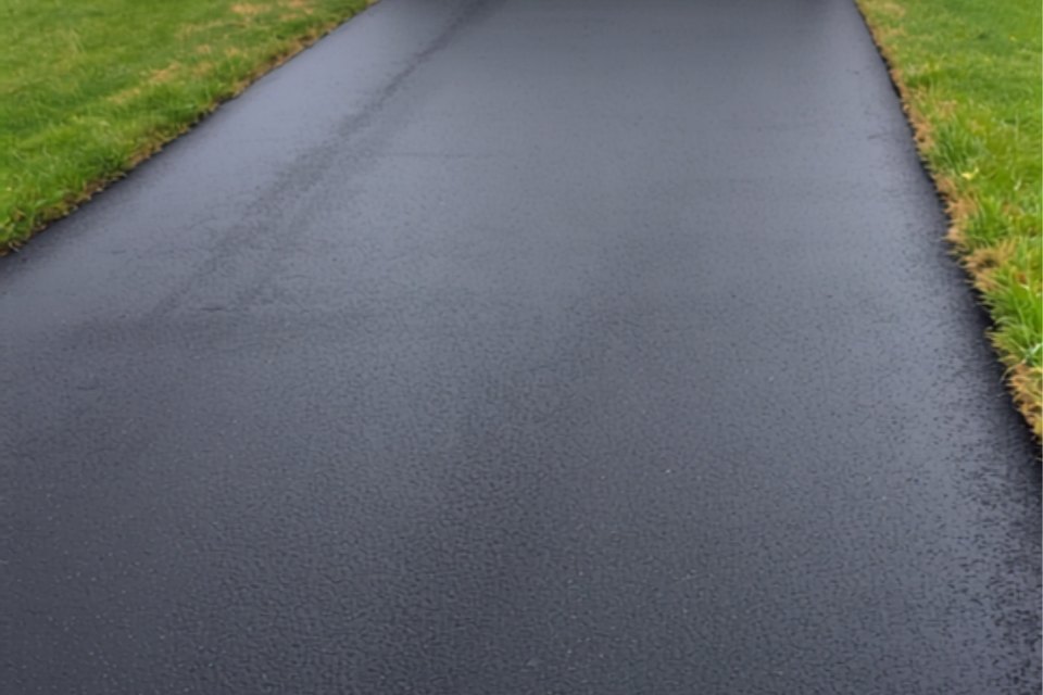 Even black sealcoat sheen across a driveway surface with a crisp edge line