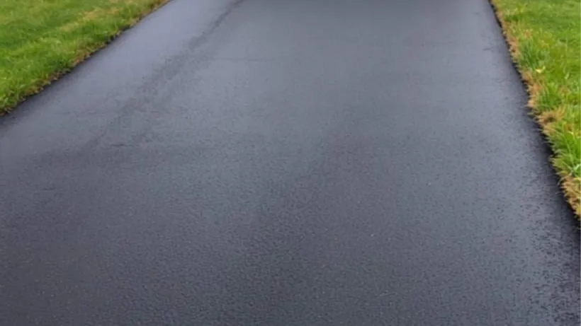 Even black sealcoat sheen across a driveway surface with a crisp edge line